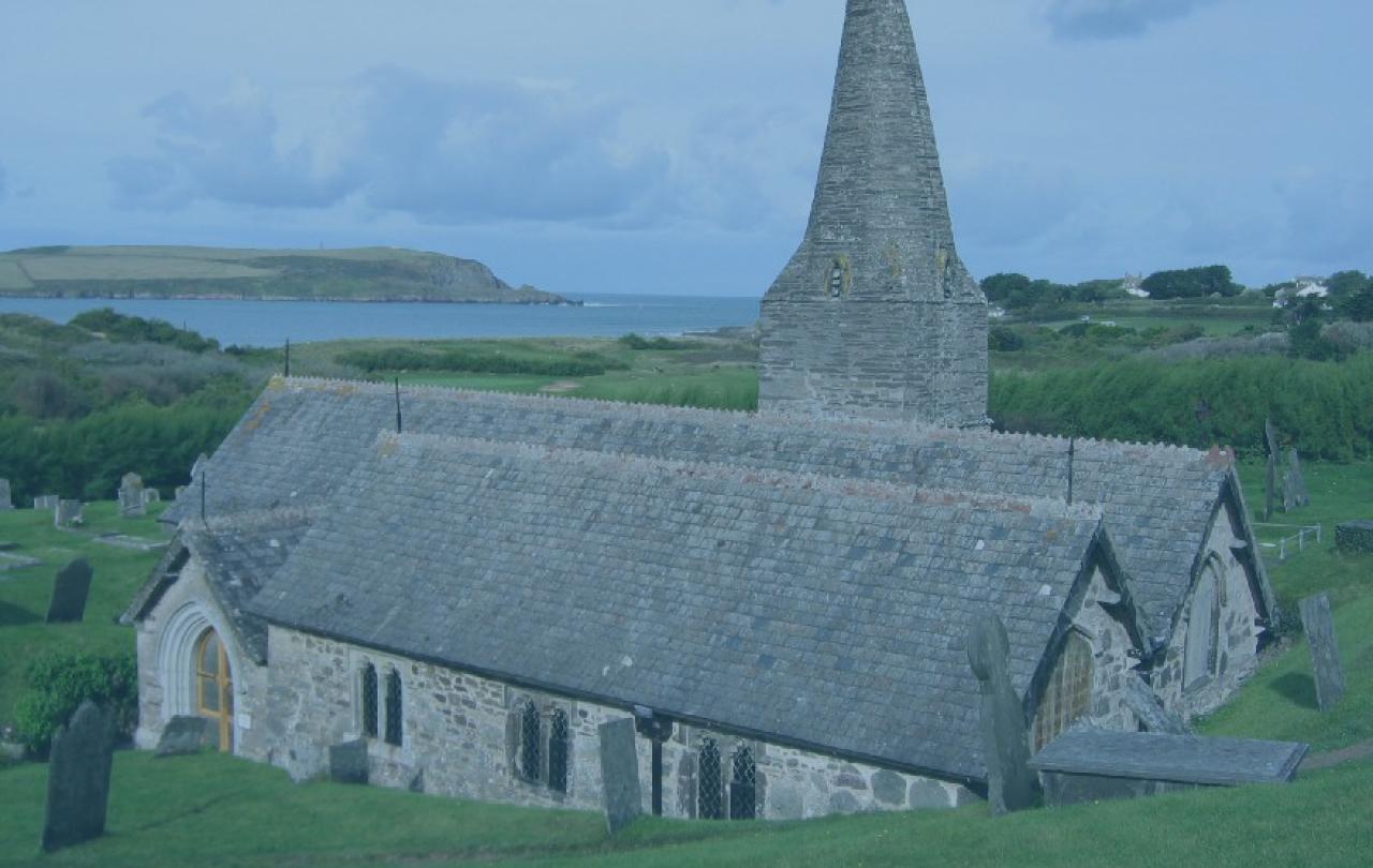 A stone church and tower emerge from the hillside with the sea in the distance.