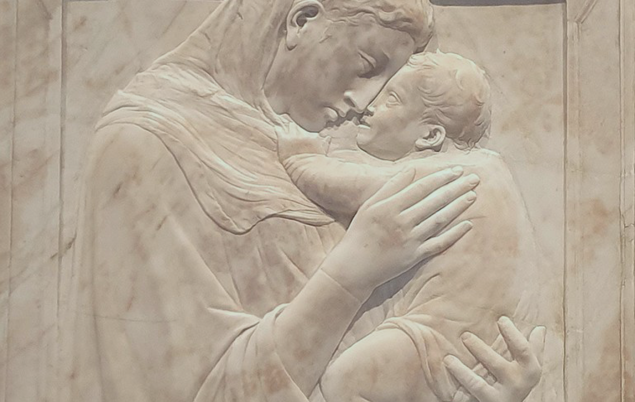A relief sculpture shows the Madonna hold the infant Christ close to her face.