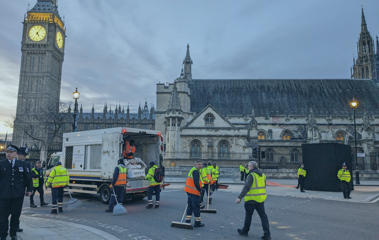 A team of street sweepers clear up the road after the coronation procession, outside the Houses of Parliament.