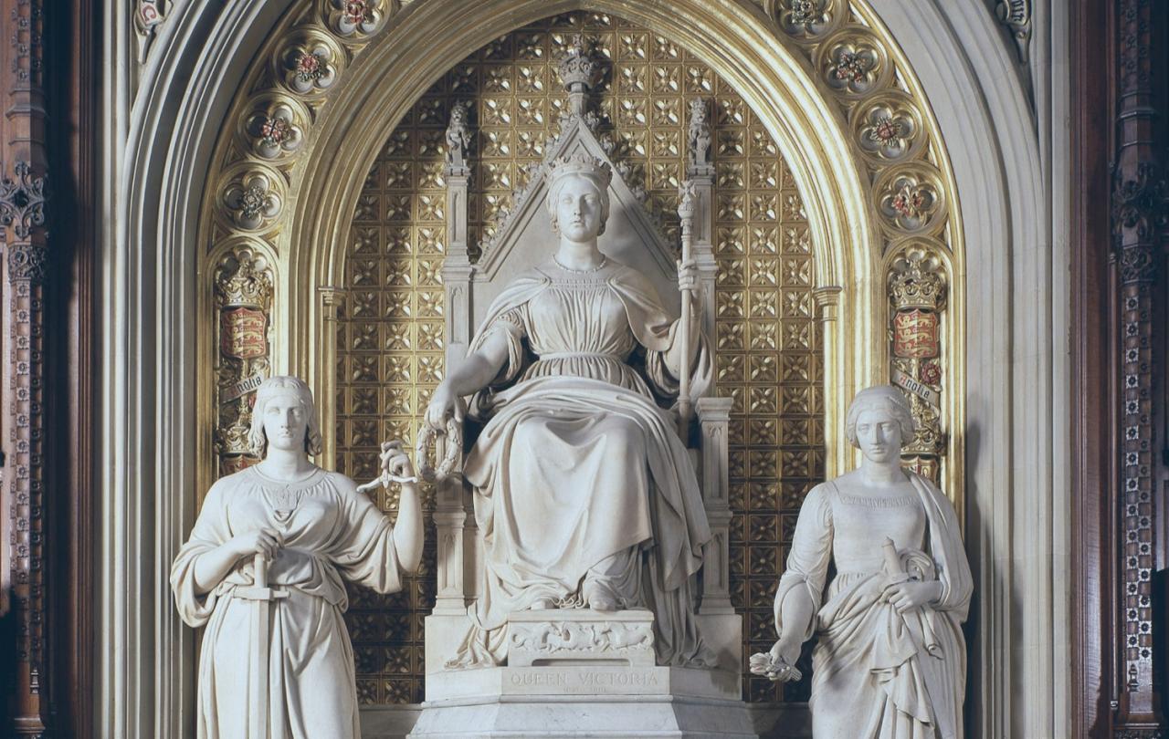 Under a gilded arch, a statue of a young Queen Victoria sits, between two standing figures.