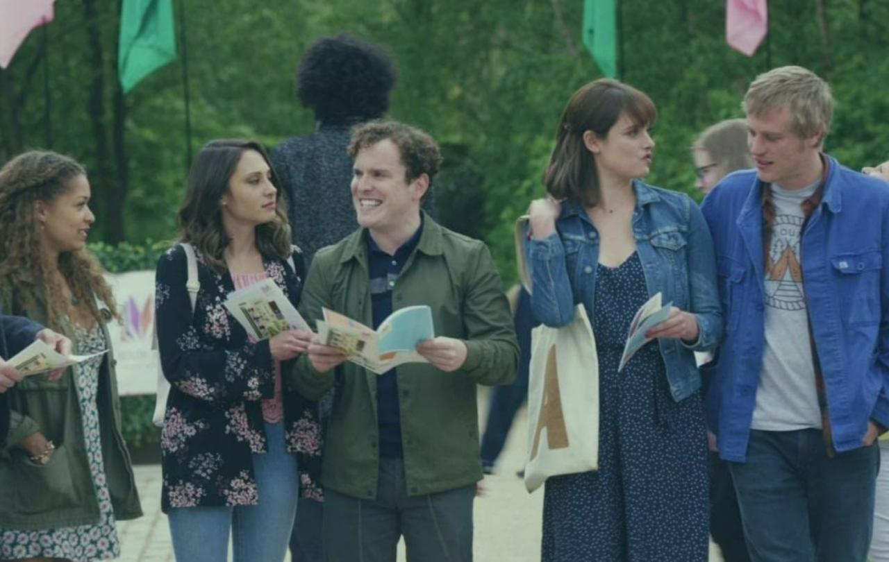 A row of young people stand and talk to each other