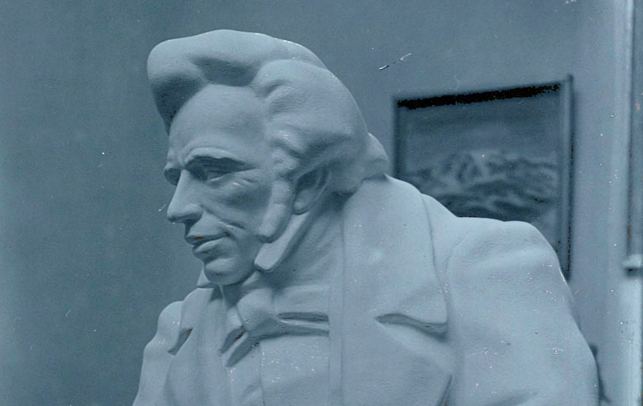 A sculpture of a early 19th century man with a quiff and sharp suit.