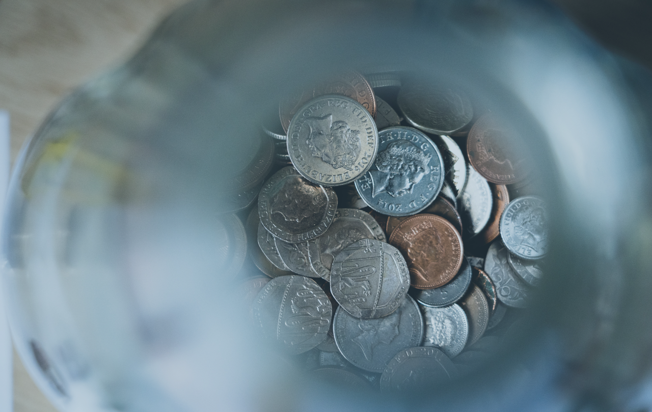 A pile of coins in focus at the bottom of an out of focus glass tube.