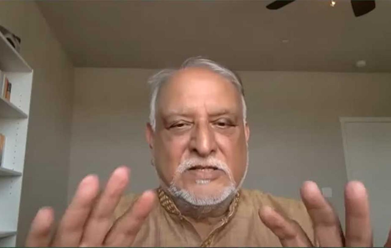 A man holds both hands up as he talks to a web cam