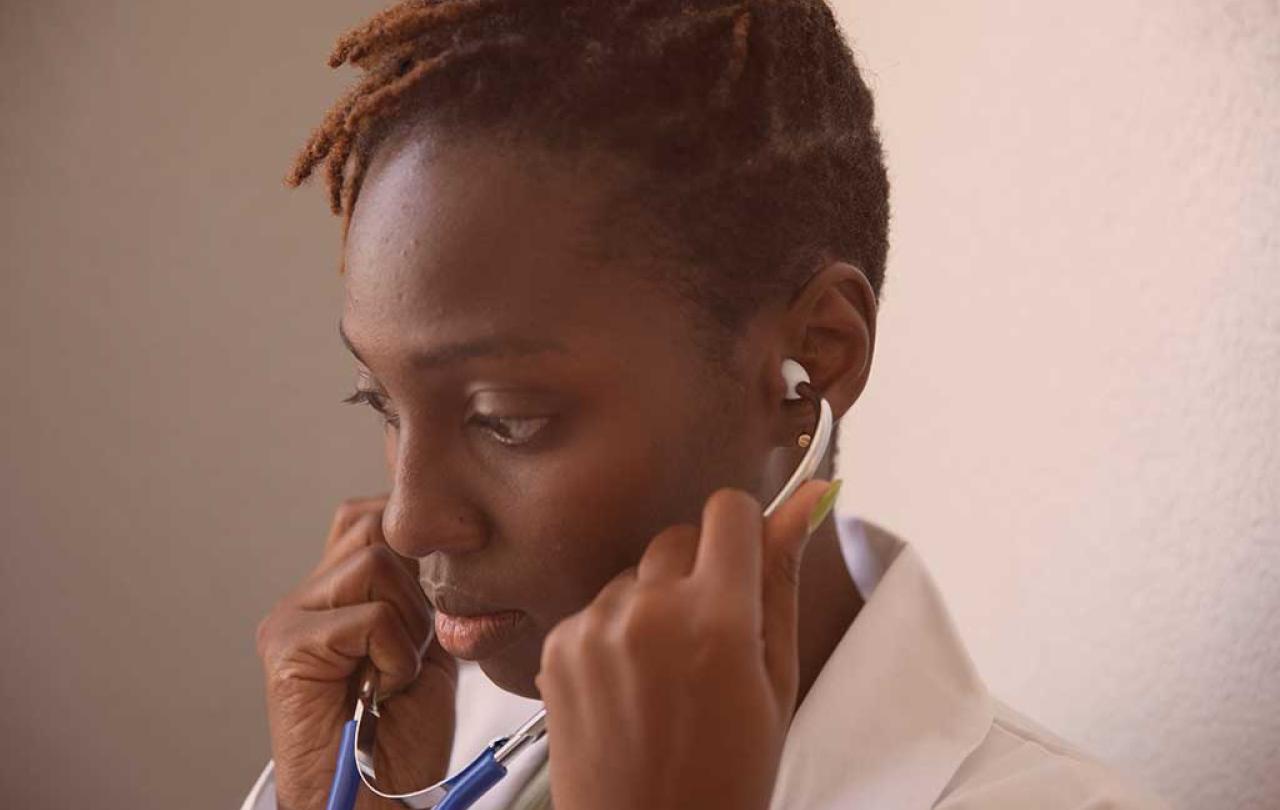 A doctor looks thoughtful will holding a stethoscope to their ears.