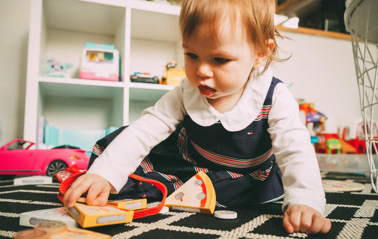 A baby plays with wooden toys on a carpert.