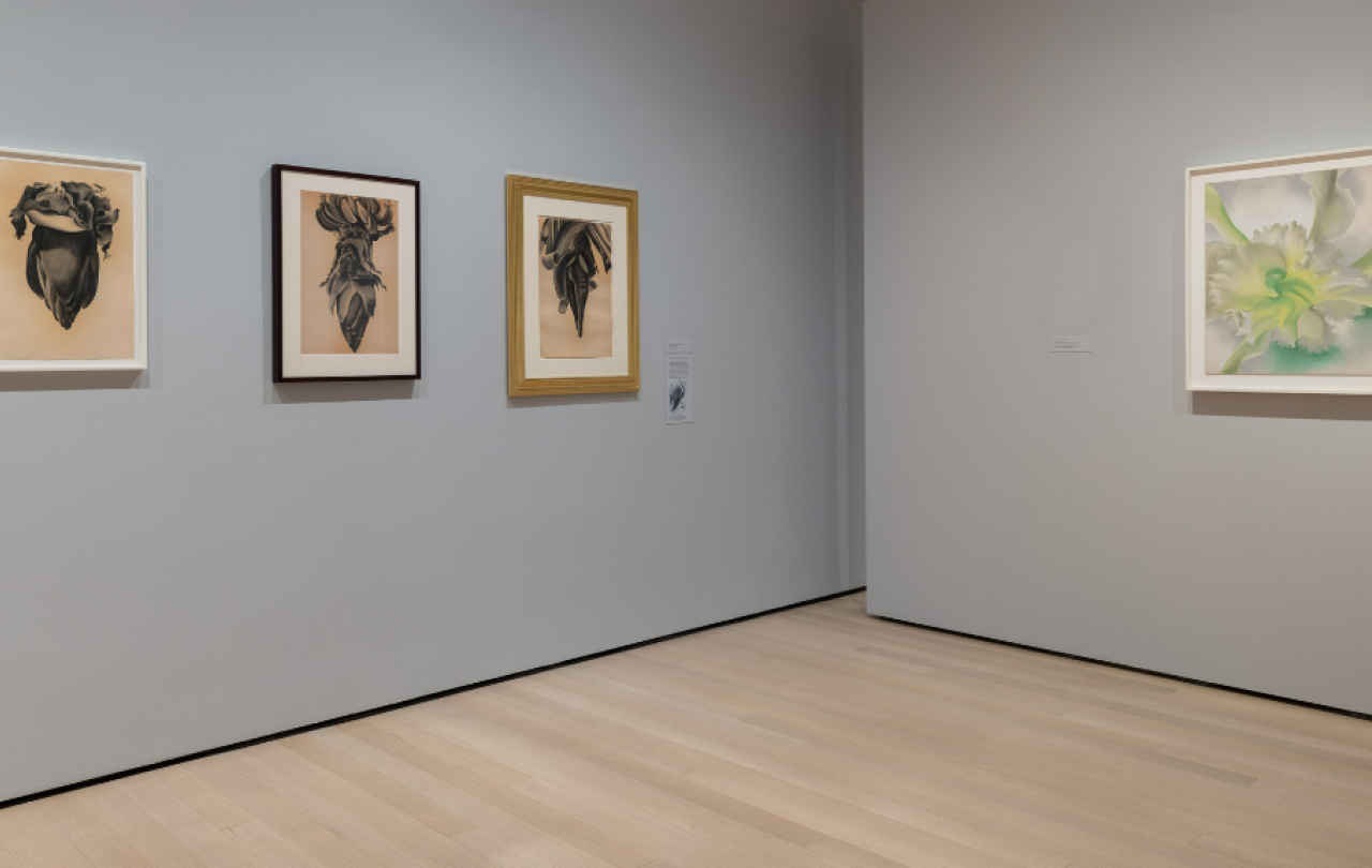 A corner of an art gallery displays three pictures to one side and one to the other.
