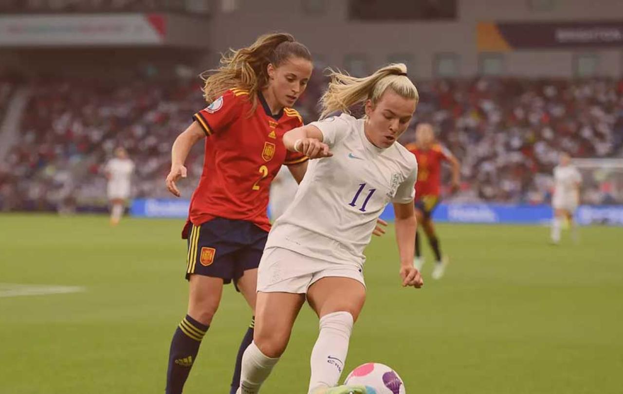 Two footballers run in step as one tries to tackle the other