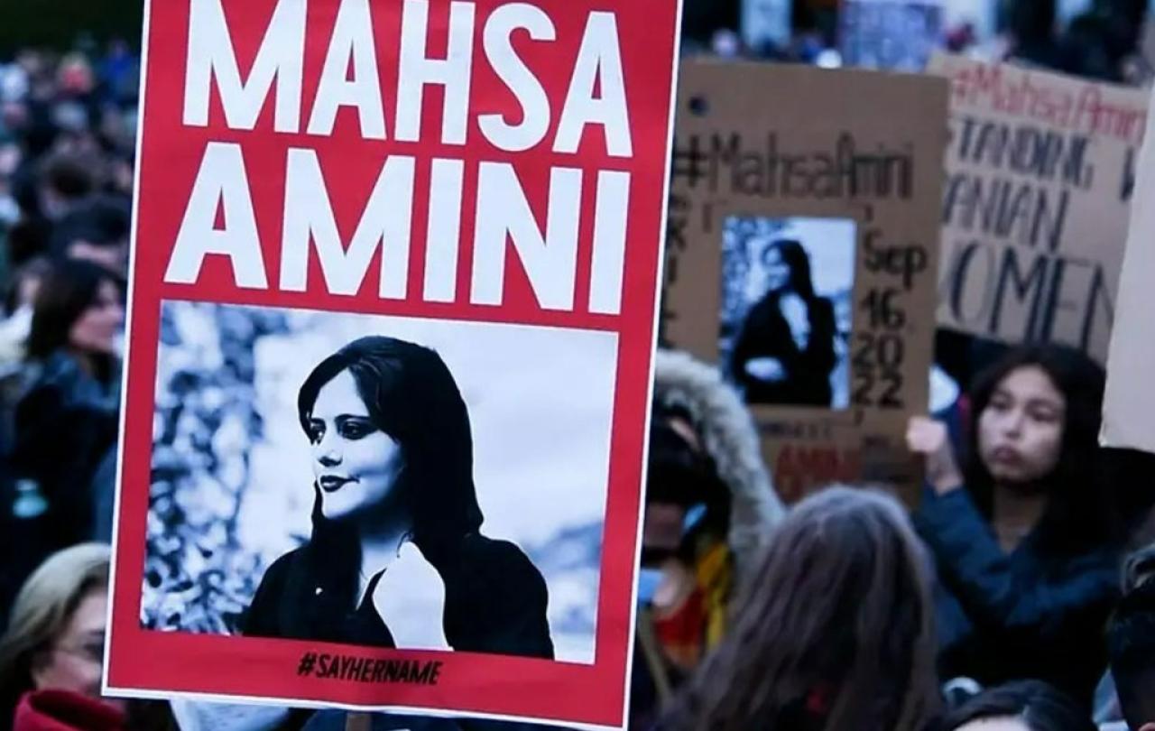 A protester holds a red placard bearing the name and image of Mahsa Amini