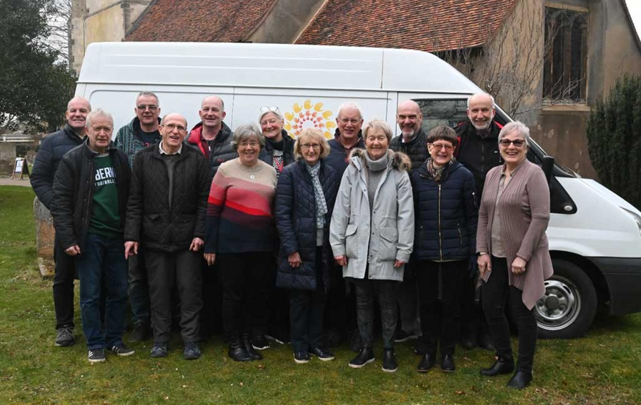 A group of people stand in front of the side of a van marked 'Furniture Friends.