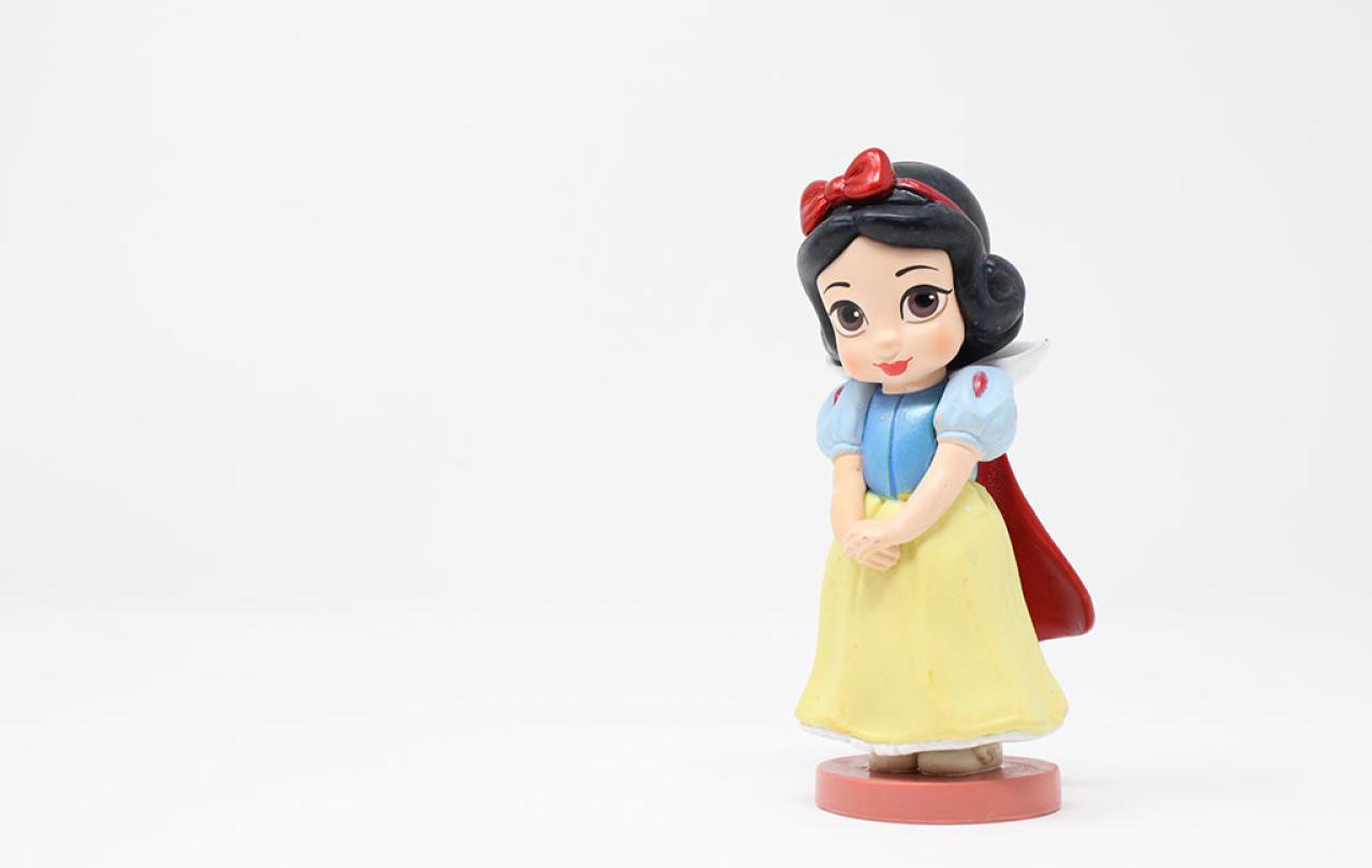 A plastic wind-up Snow White toy stands to the right of the photo, with hands clasped waiting