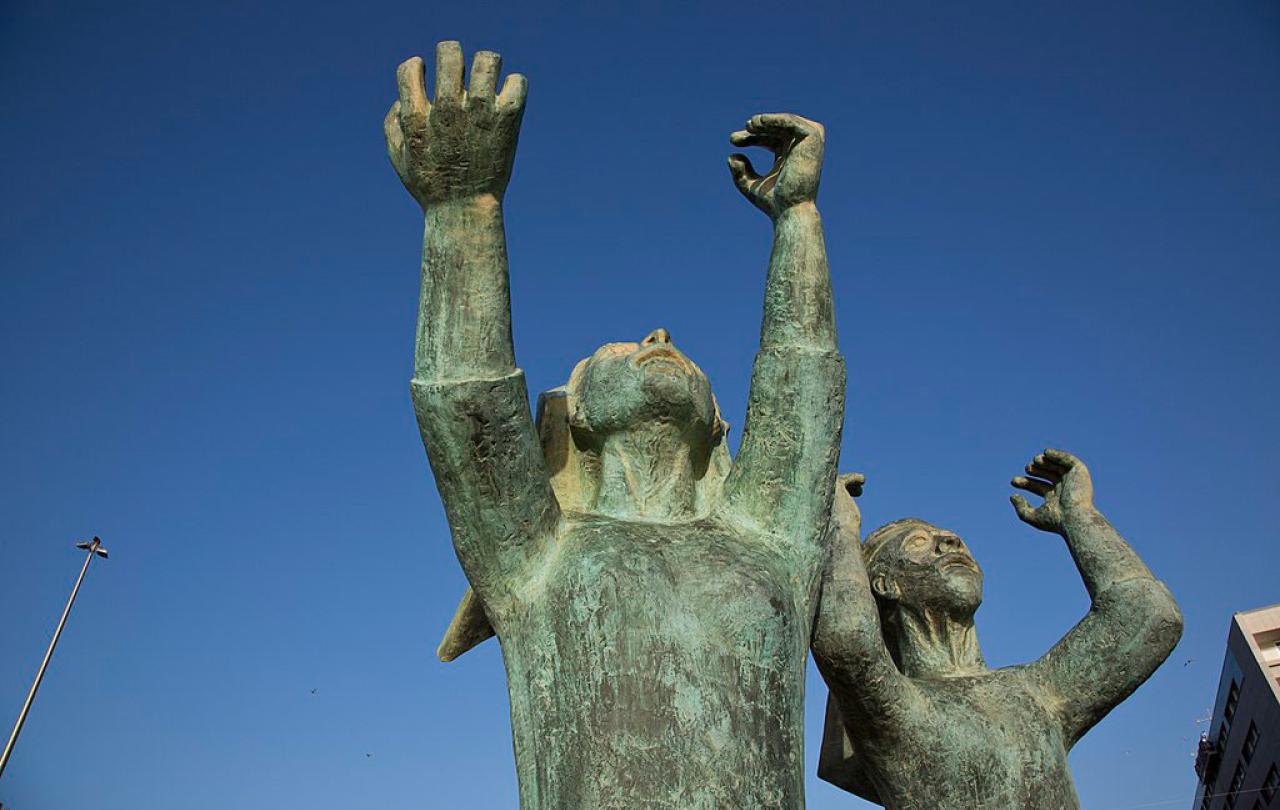 A sculpture shows mourning women raising hands and fists to the sky.
