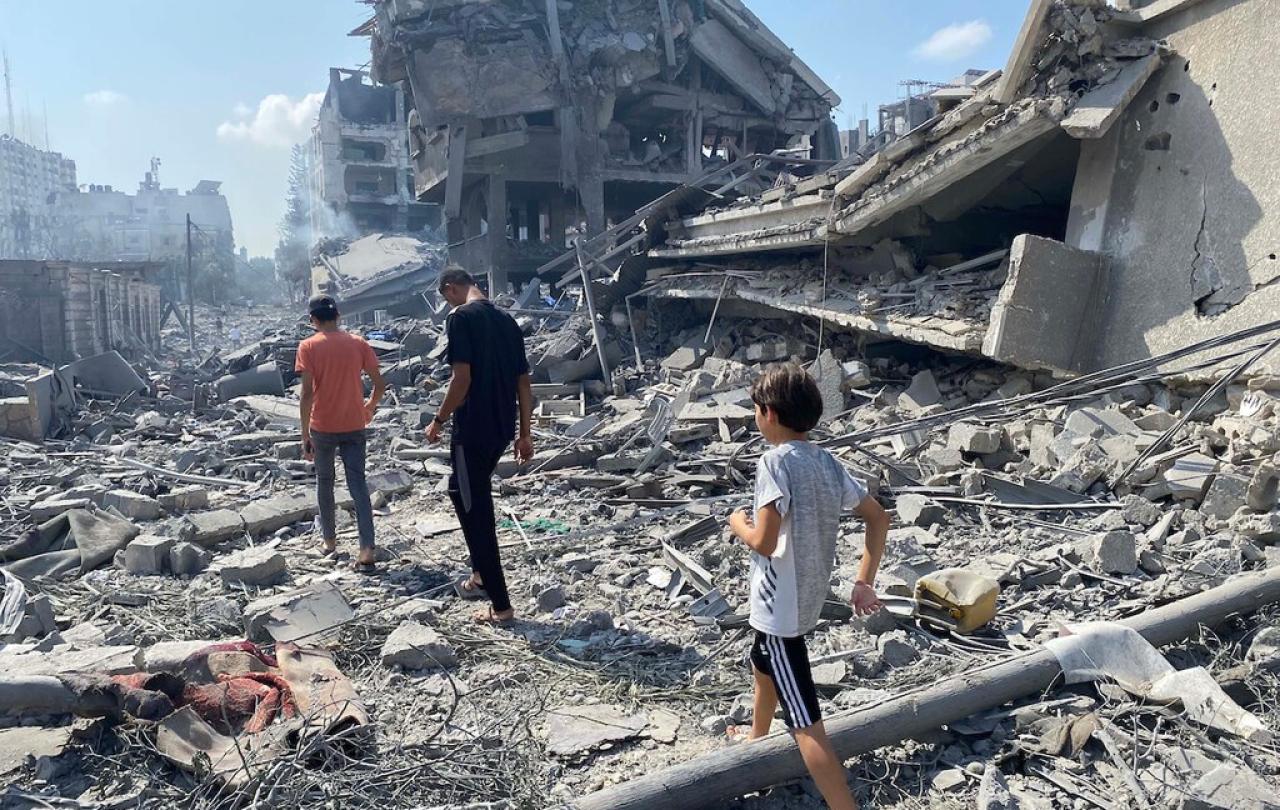 People walk across the rubble beside a recently bombed building.