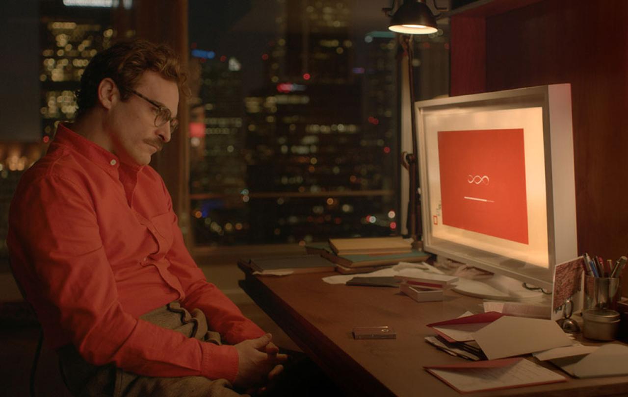 A man in a red shirt slumps in his seat while a computer screen shows a dialogue screen