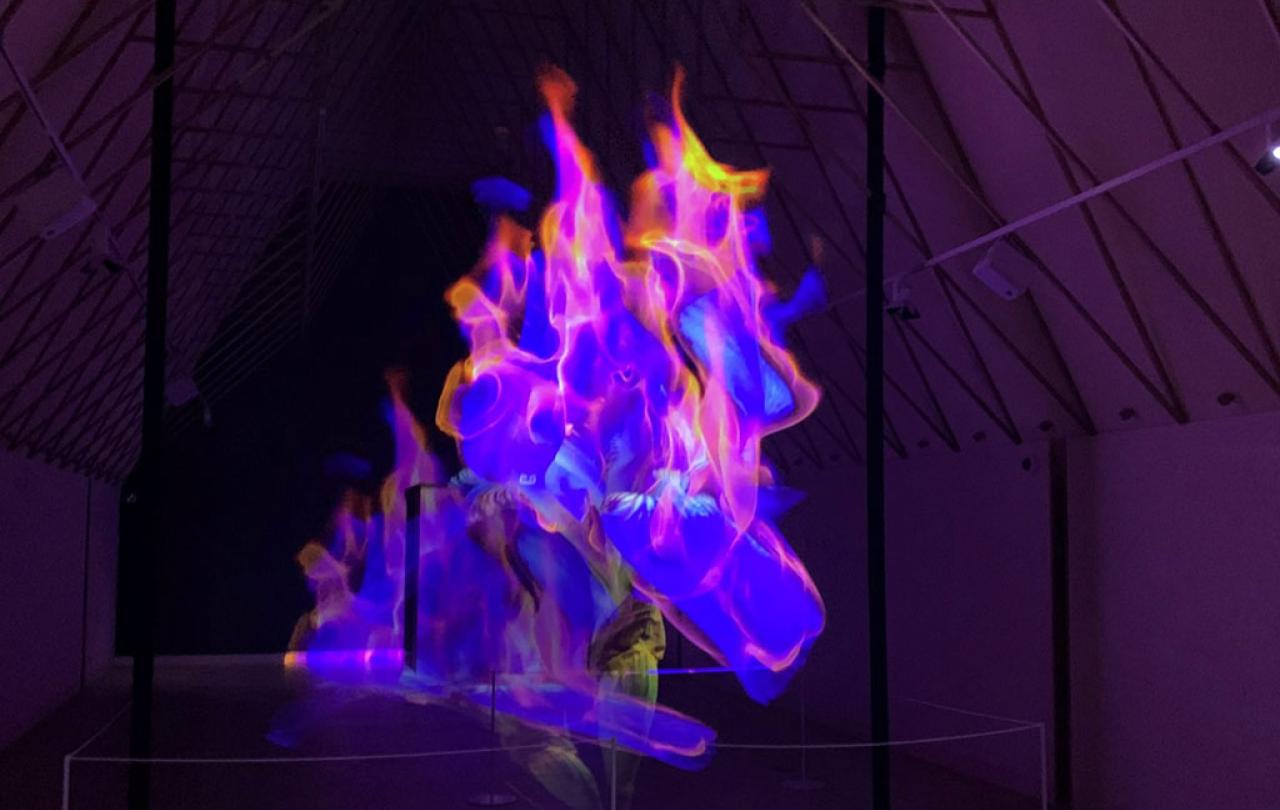 A art installaton showing purple and pink flame-like shapes moving in a darkened room