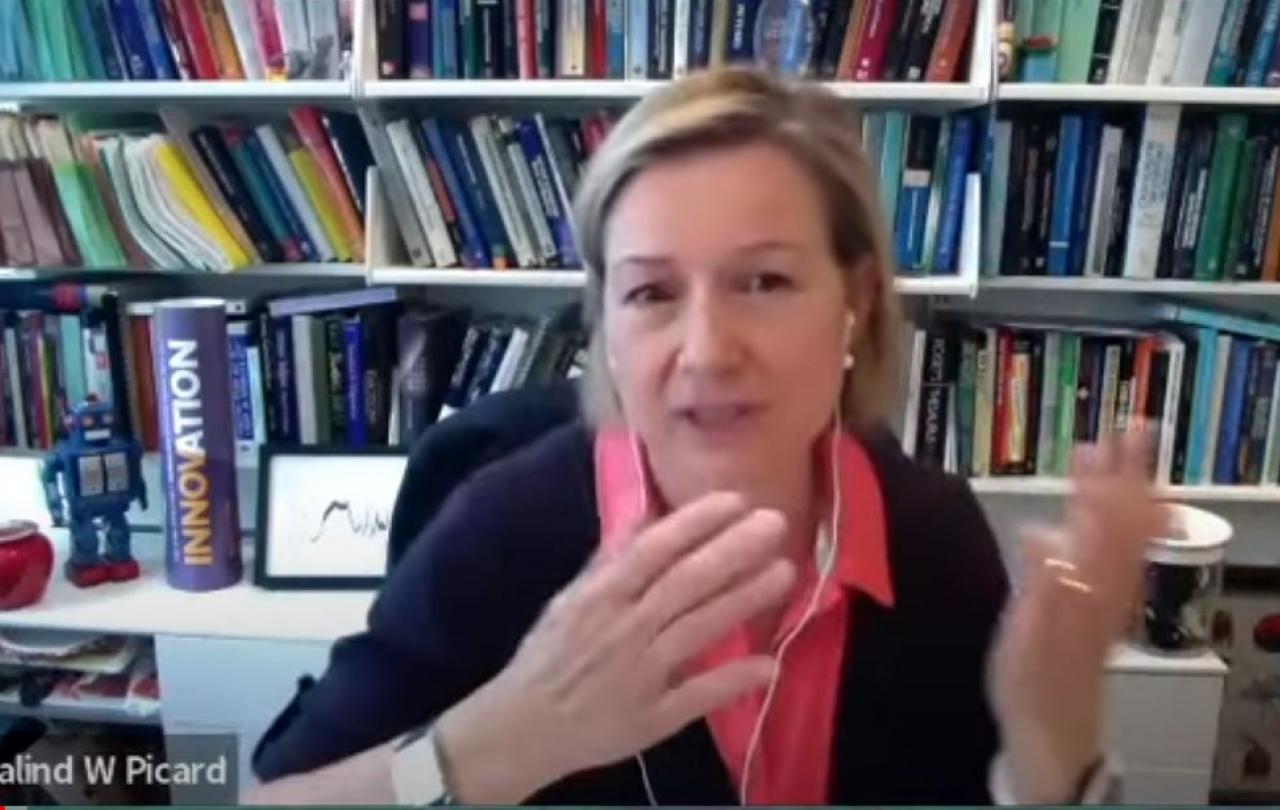 a woman at a desk video call gestures with her hands to make a point.