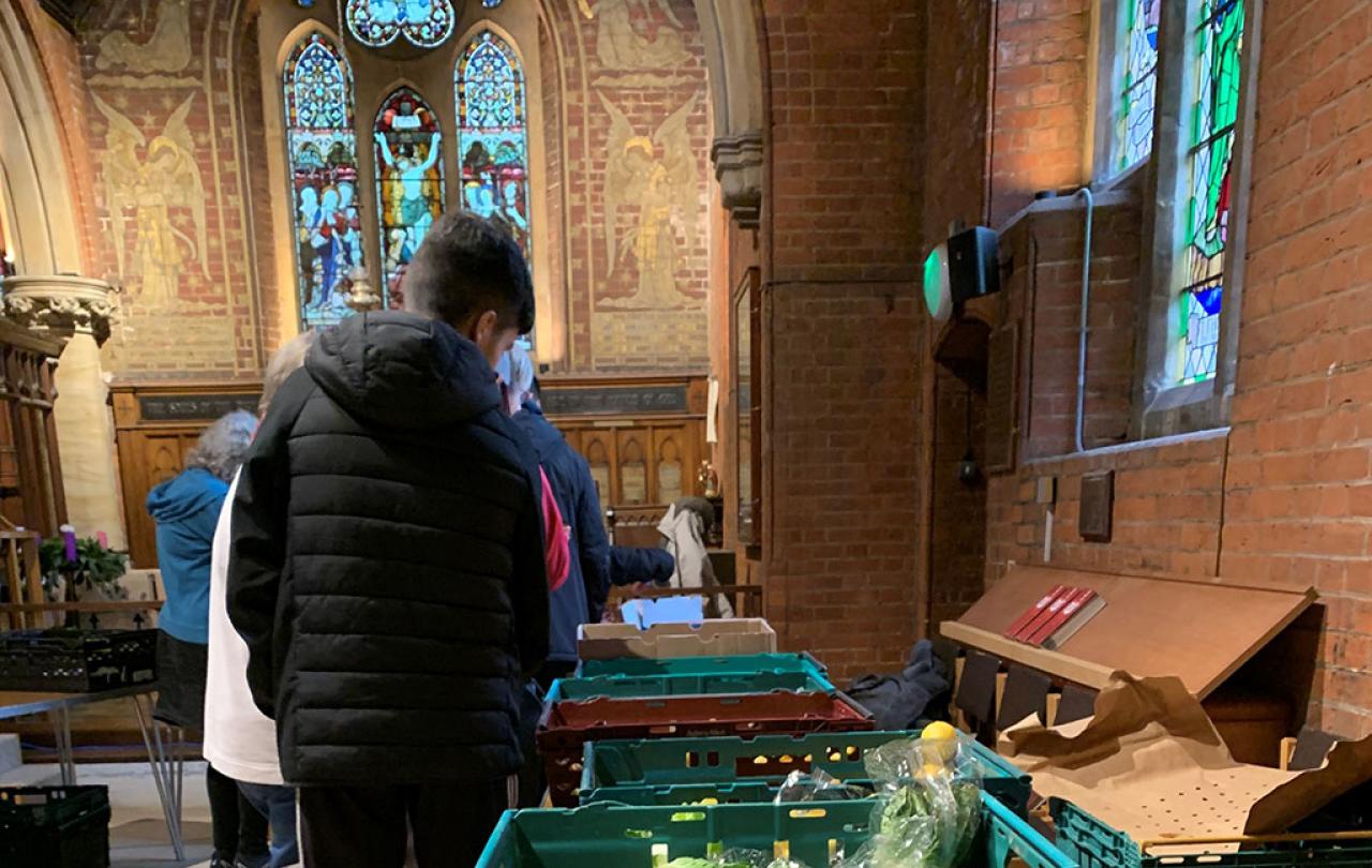 clients of a charity queue beside a table of suppliers in a church