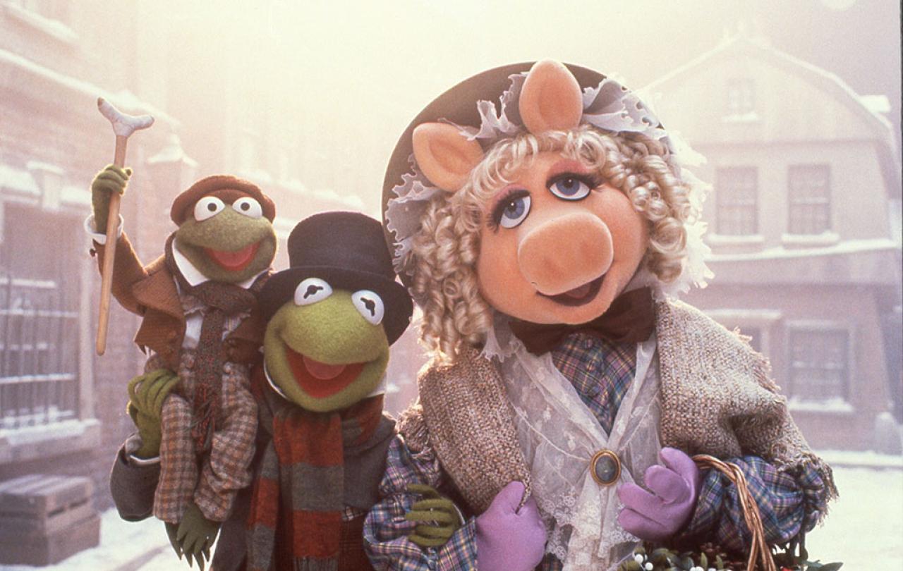 Muppet characters dressed as Dickensian characters stand in a snowy street.