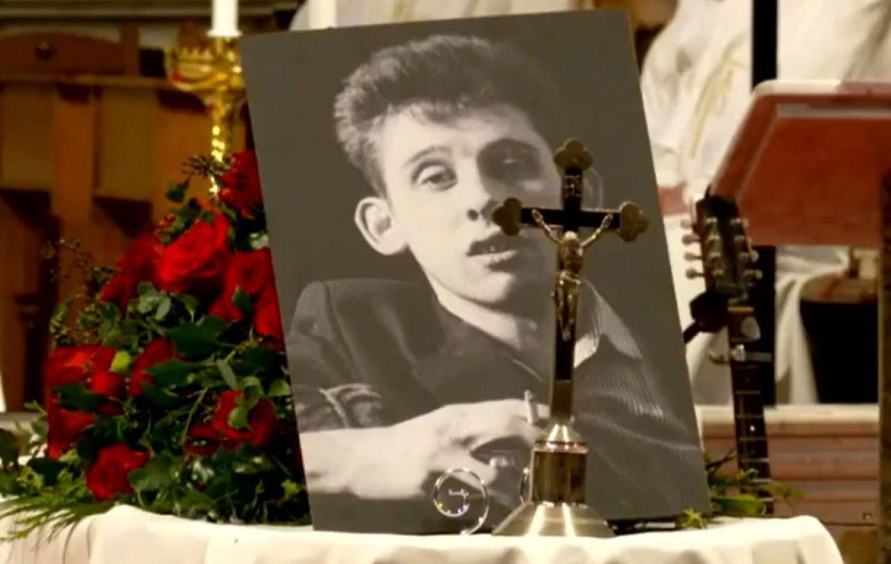 Upon his draped coffin, a picture of Shane MacGowan and a crucifix sit