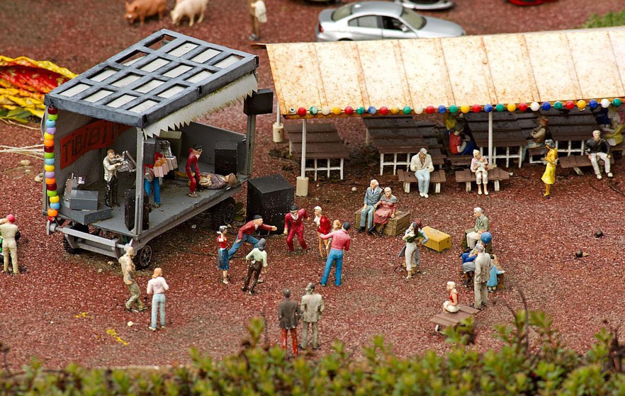 A miniature tableau depicts a band performing at a concert as people dance and others watch from a marque.