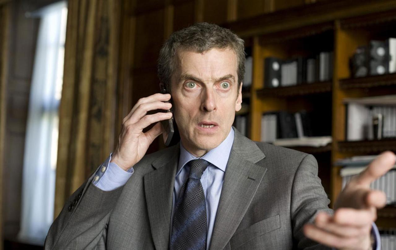 An irate man holds a mobile phone to his ear while gesticulating with his other hand.