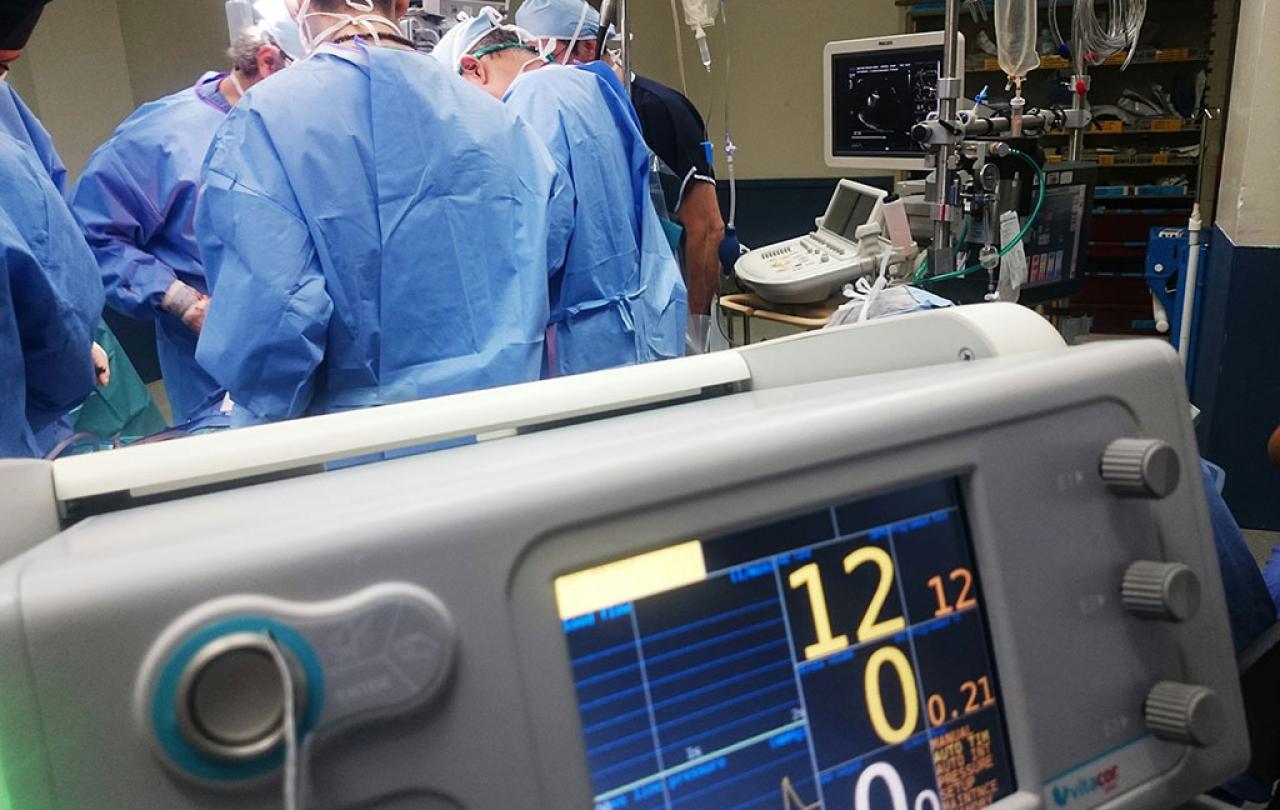 While surgeons operate in the background a digital display shows numbers in the foreground