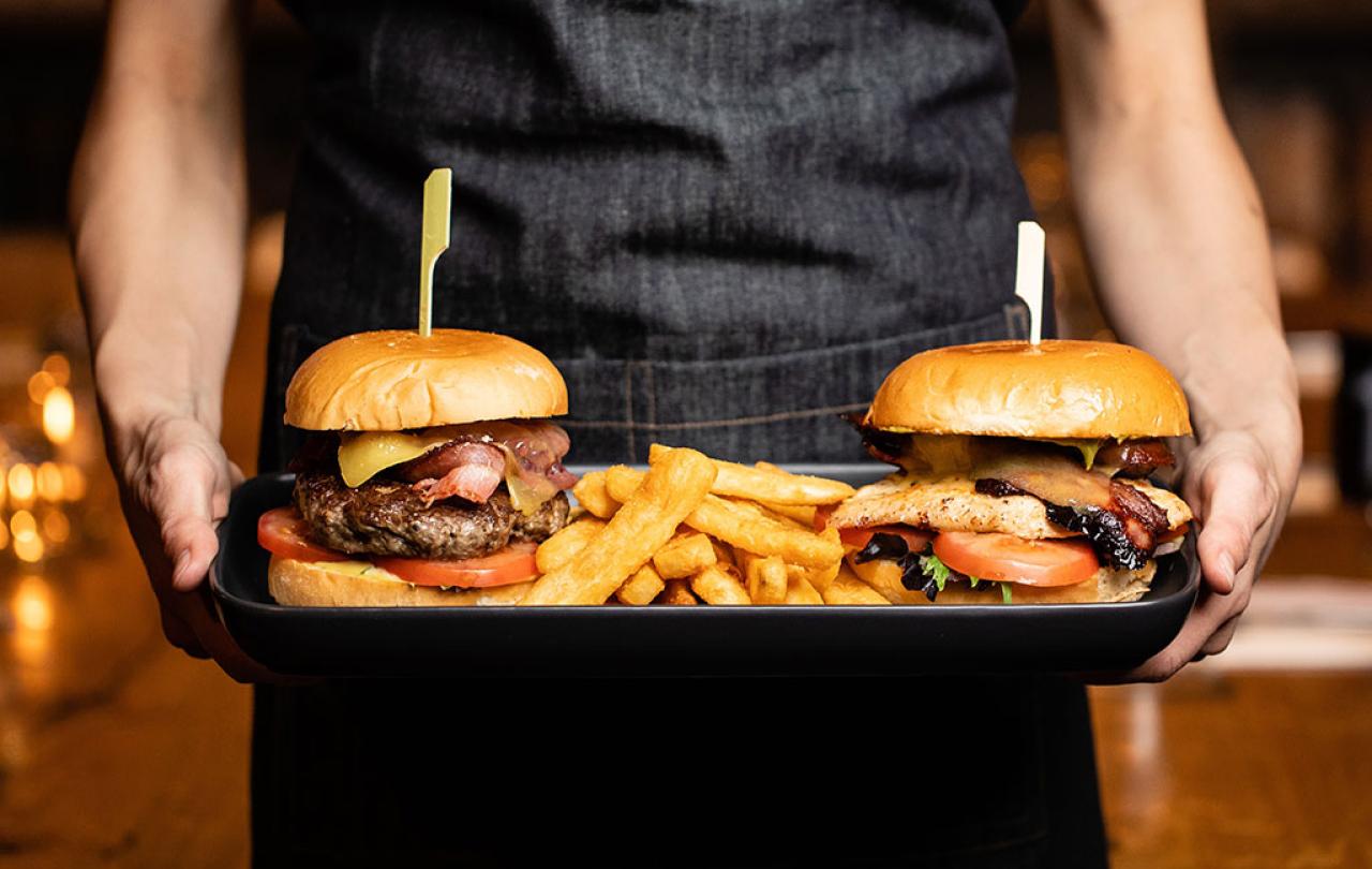 Two stuffed cheeseburgers are carried on a tray.