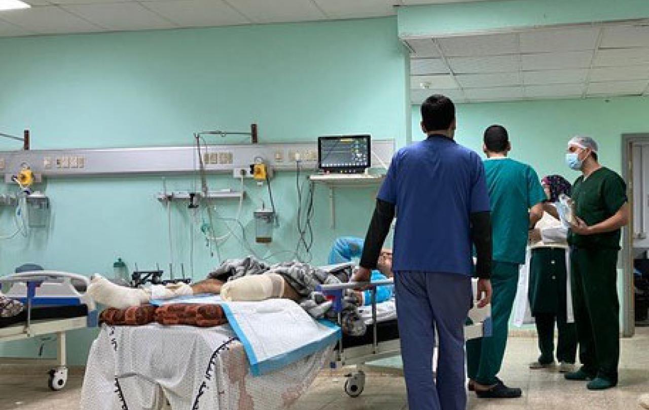 Medical staff stand beside a bed in which a man lies with an amputated leg.