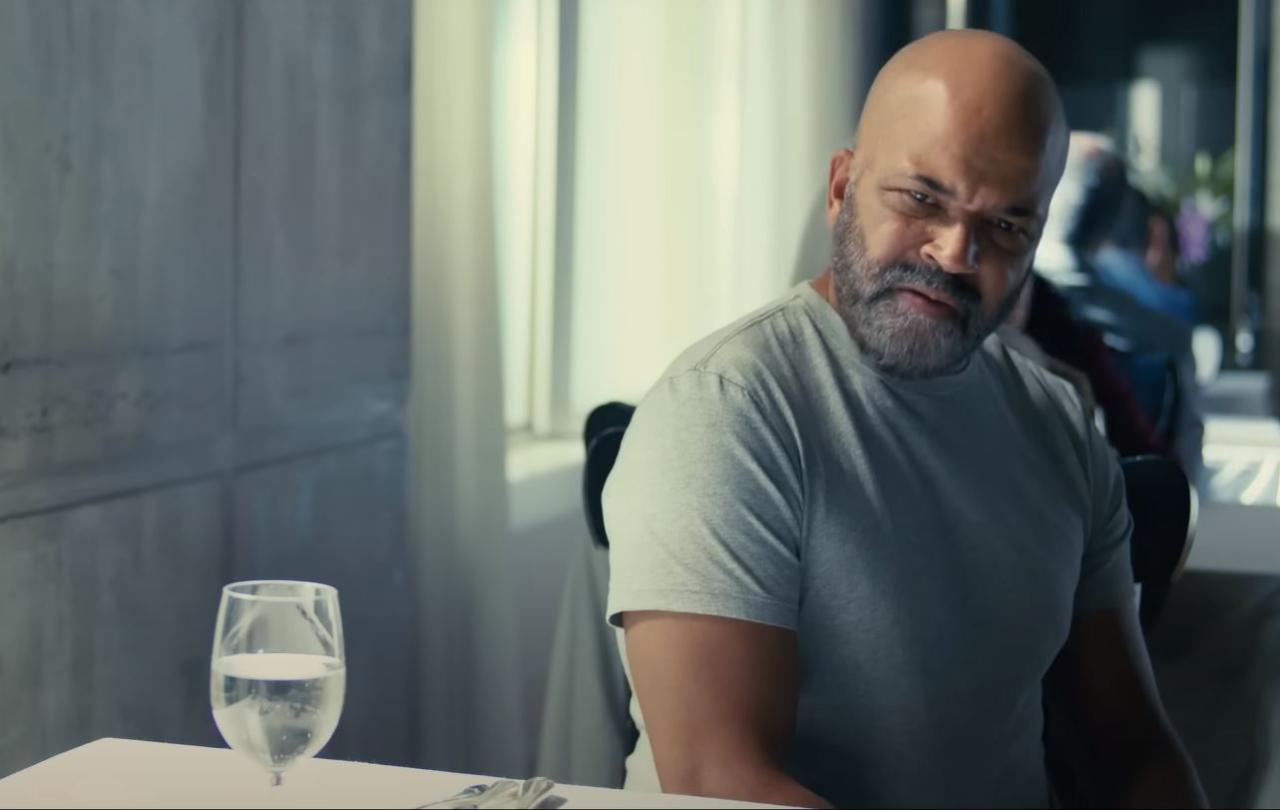 A man sitting at a restaurant table turns and looks aside.