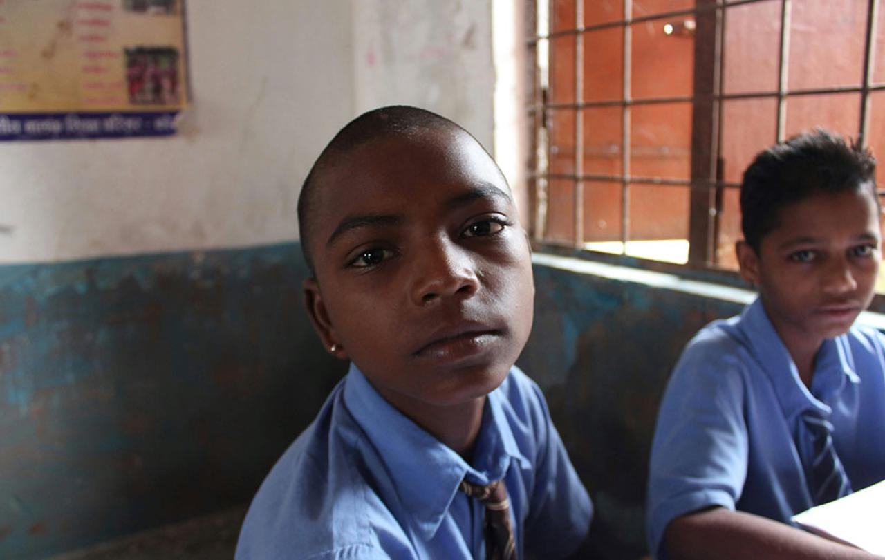 A pupil in a classroom looks around and into the camera.