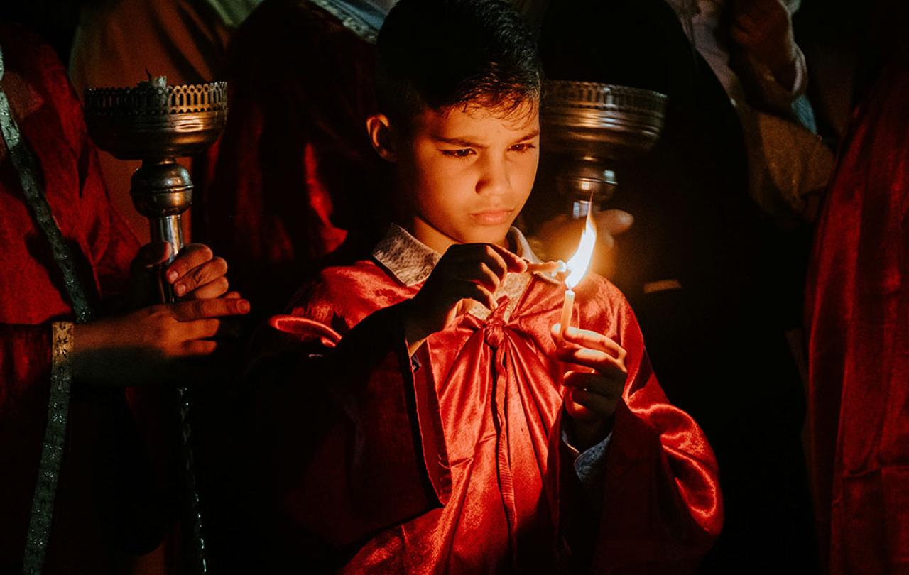 A boy concentrates hard as he holds one candle to another to light it.