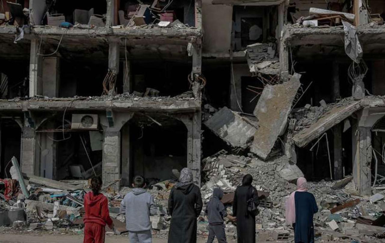 A family look at the concrete shell and remains of a bombed building.