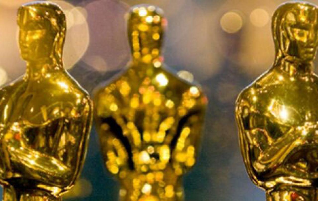 A closely cropped group of gold Oscar statues showing mostly their head and shoulders.