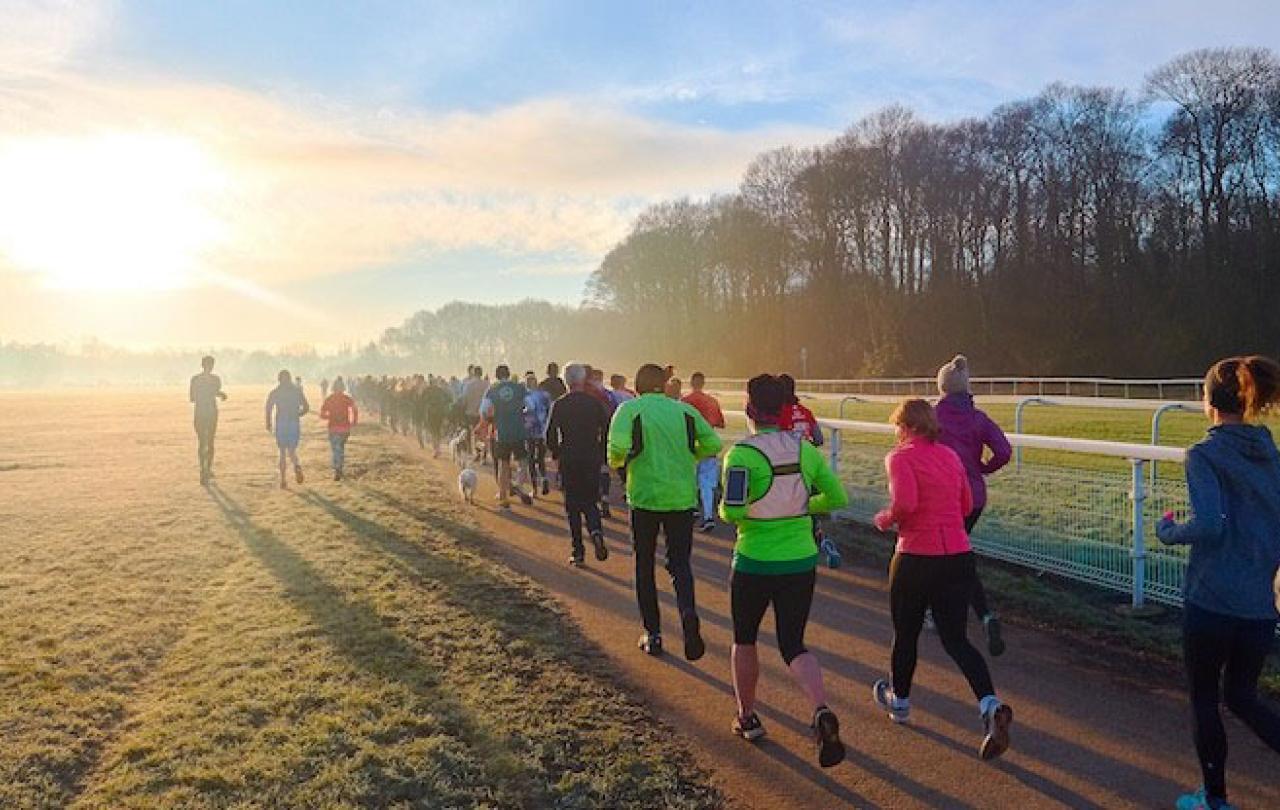 Runners jog along a path into the sunset.