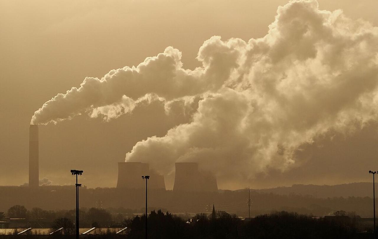 A sky line shows steam rising from a power station's chimney and cooling towers.