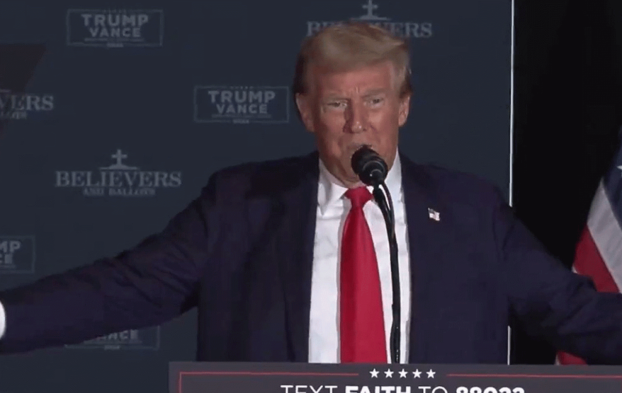 Donald Trump holds his arms out to his side while speaking.