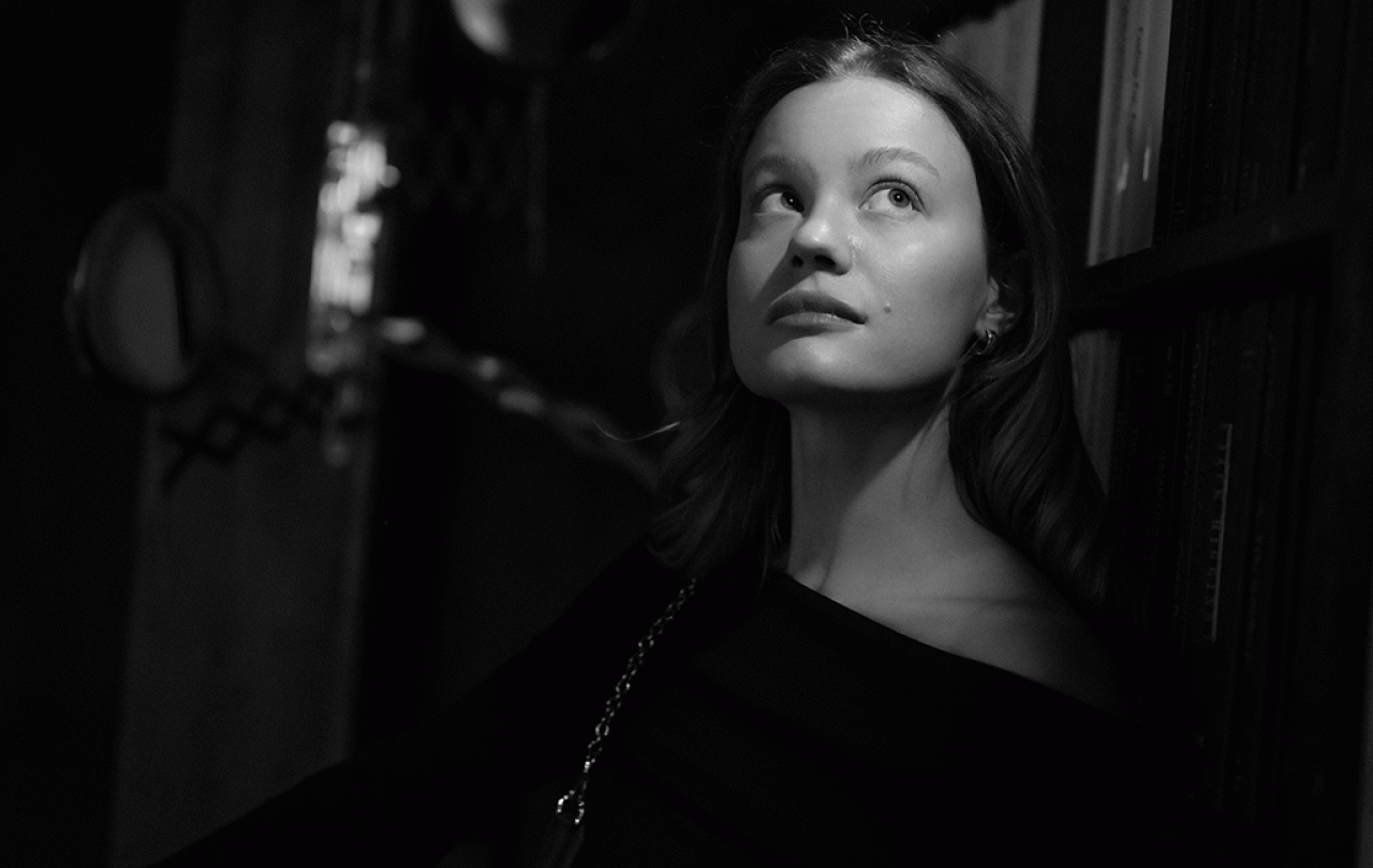 A black and white picture shows a woman head and shoulders, she is looking up and to the side in an unsure way.