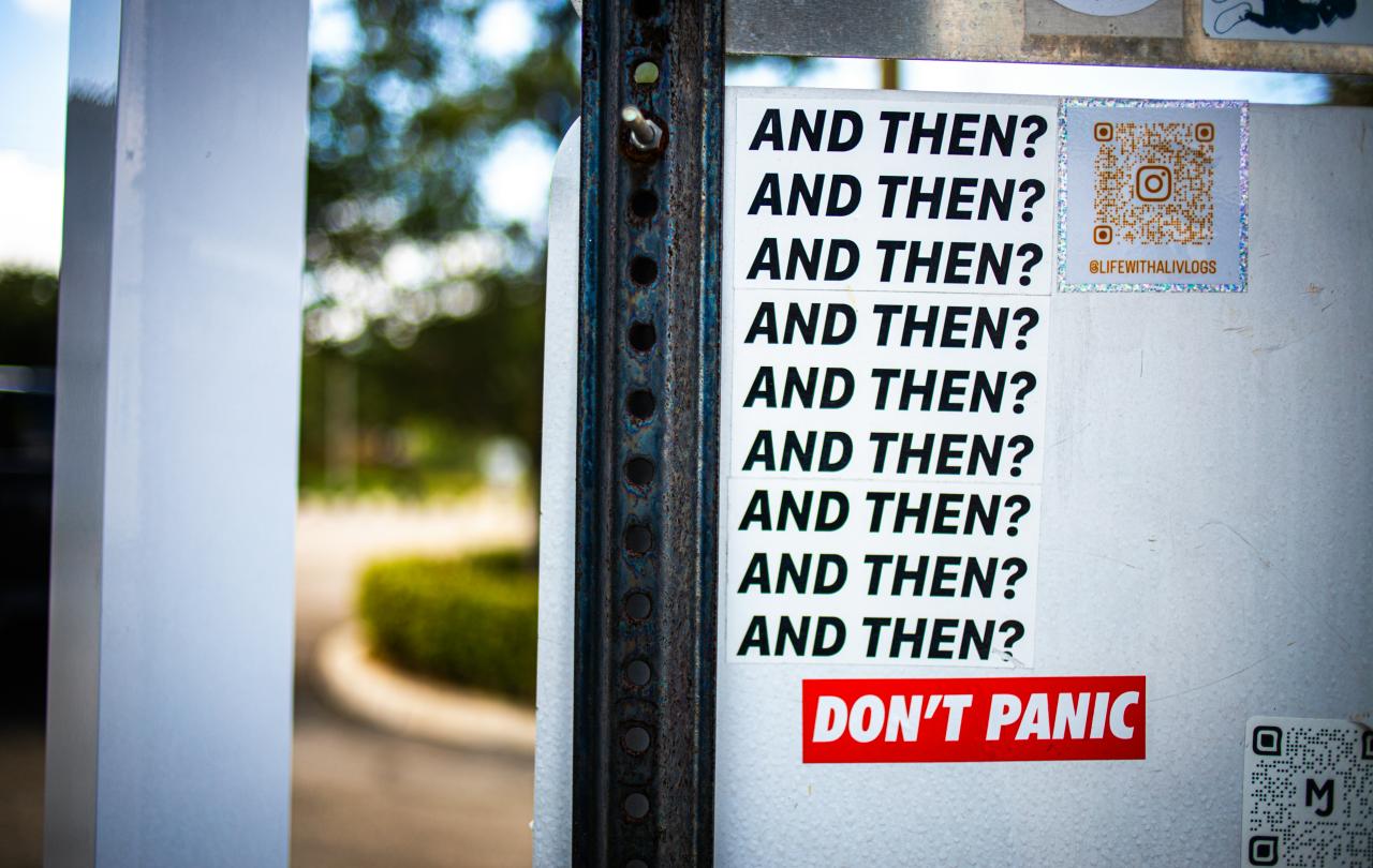 A street sticker displays multiple lines reading 'and then?'