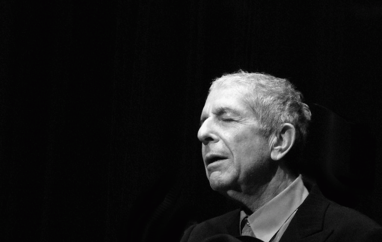 A black and white photo shows, singer Leonard Cohen to the right hand side, eyes closed and head inclined slightly upwards.