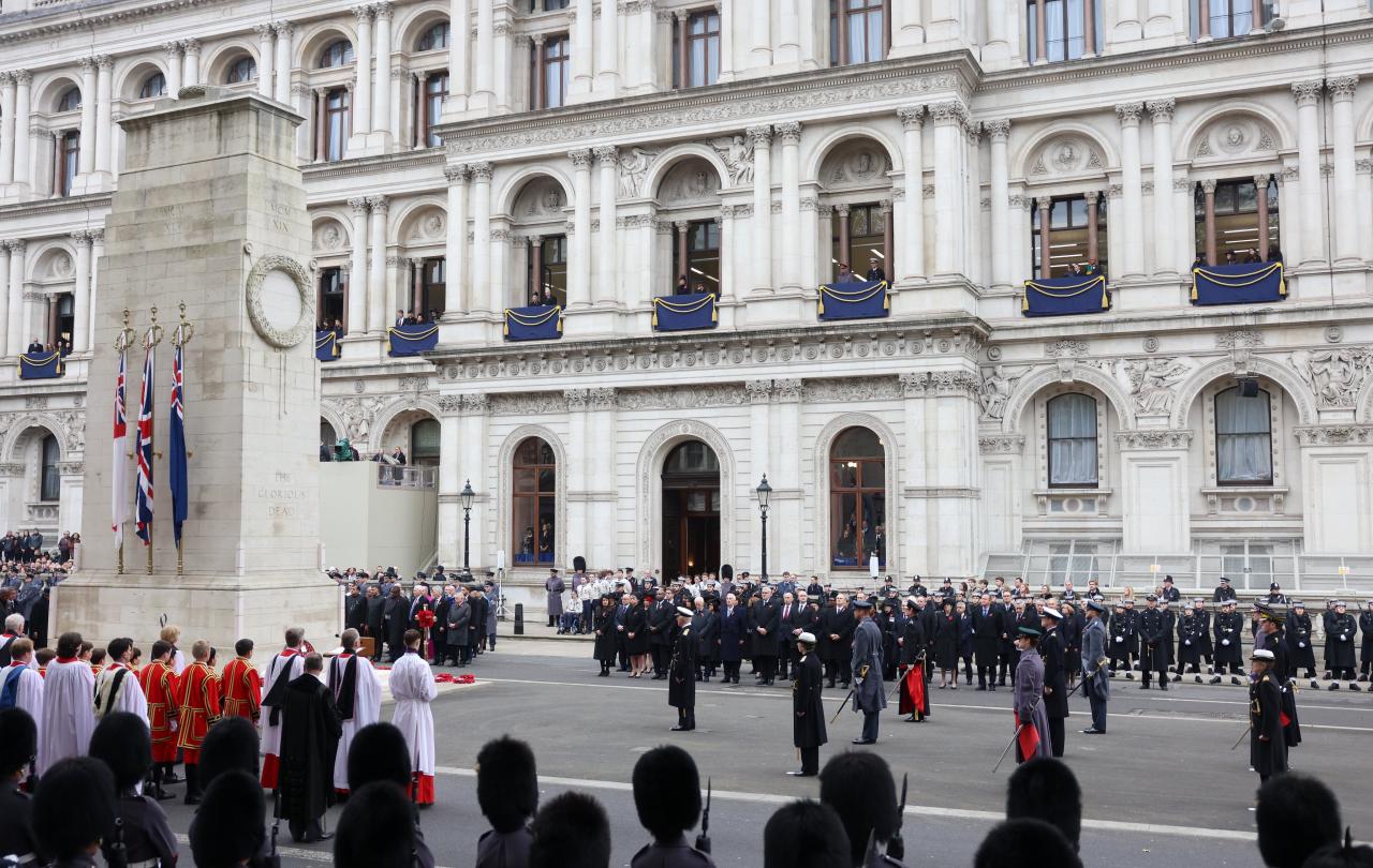 A Remembrance Sunday service stands to attention around a cenotaph.