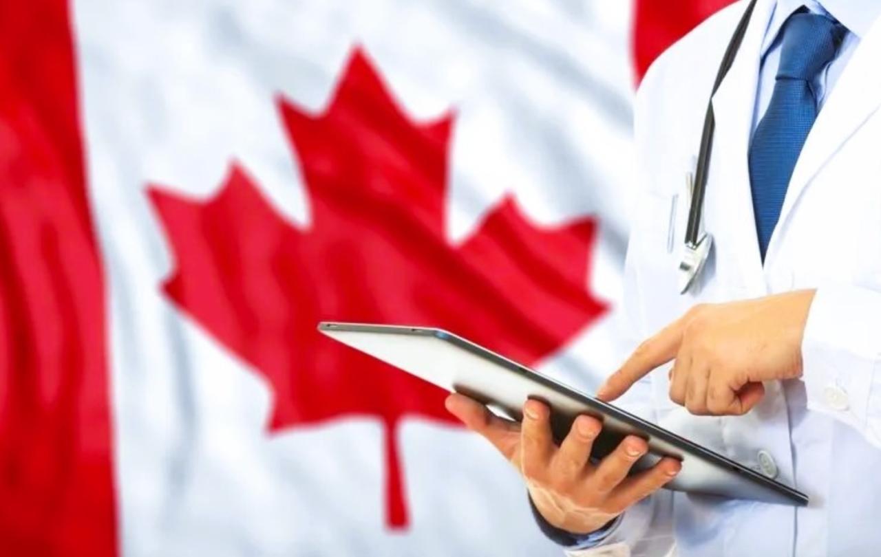 a doctor consults a tablet against the backdrop of a Canadian flag.