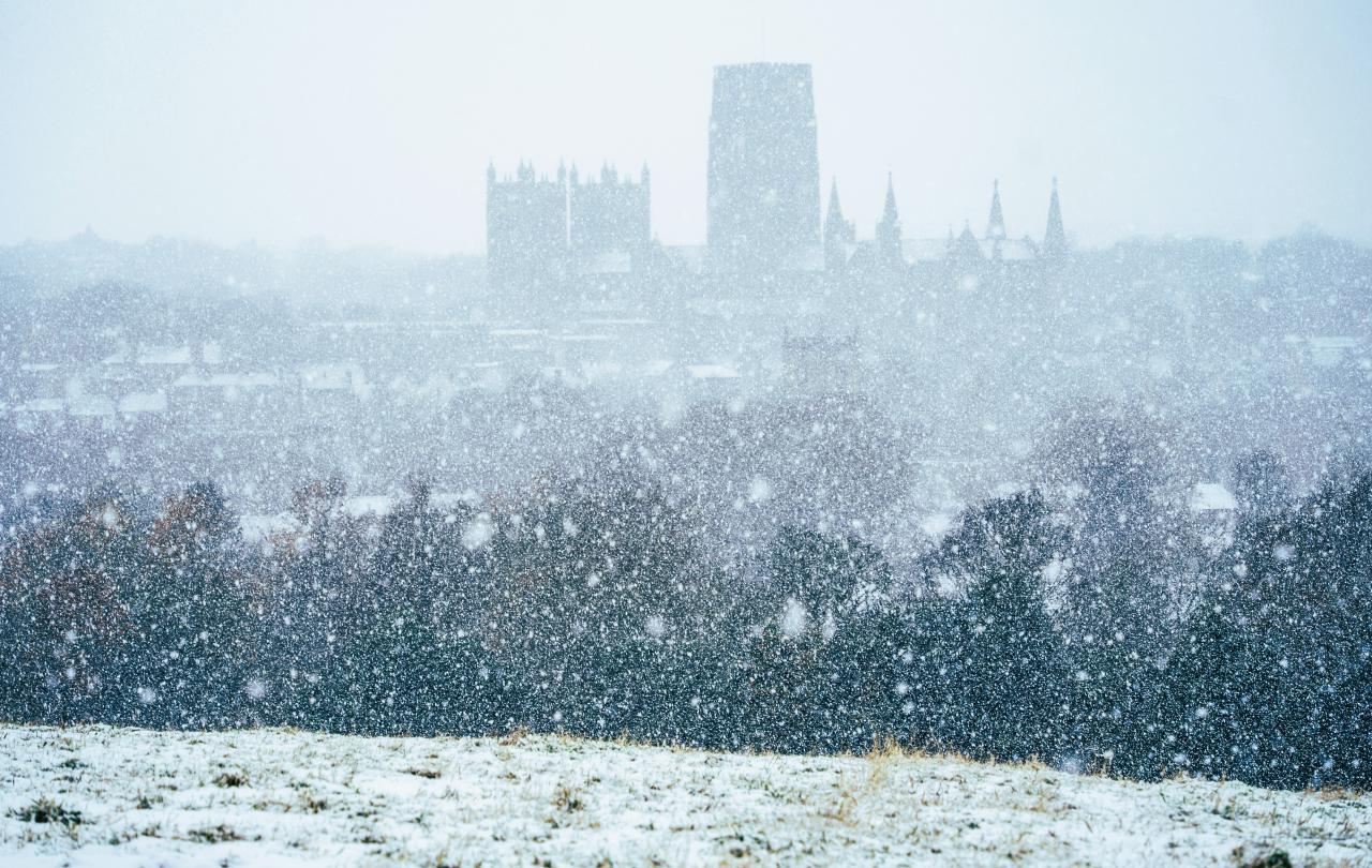 Snow falling pixilates the view from a hill towards Durham Cathedral.
