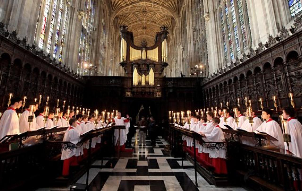 Choristers stand and sing in choir stalls in a church