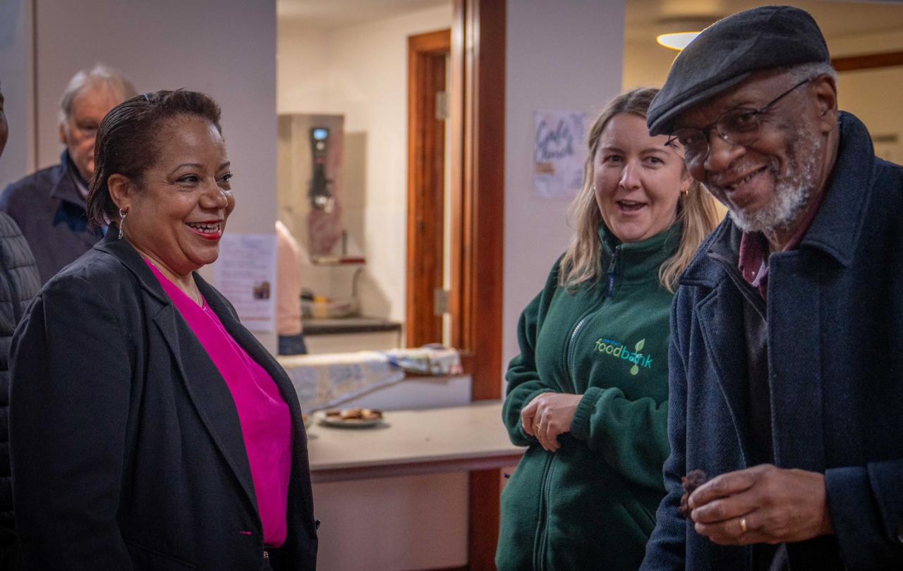 Three people stand beside a table and smile.