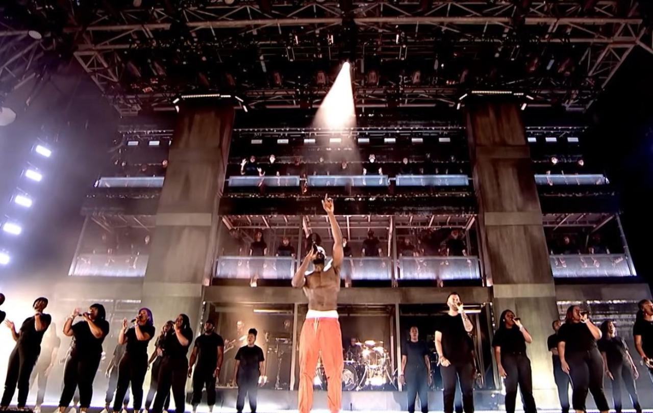 Rapper Stormzy raises a hand to heaven as he sings with a gospel choir on the Glastonbury stage.