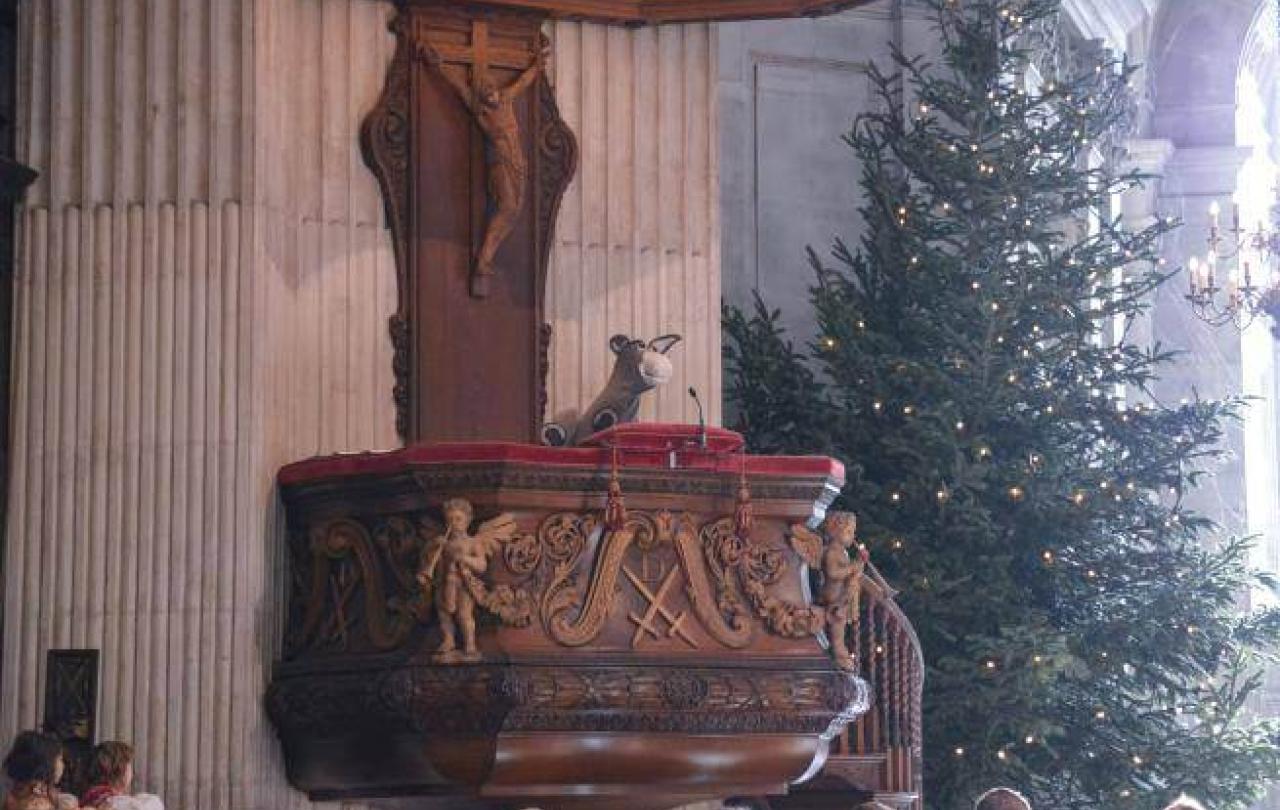 A puppet donkey peaks over the edge of a cathedral pulpit
