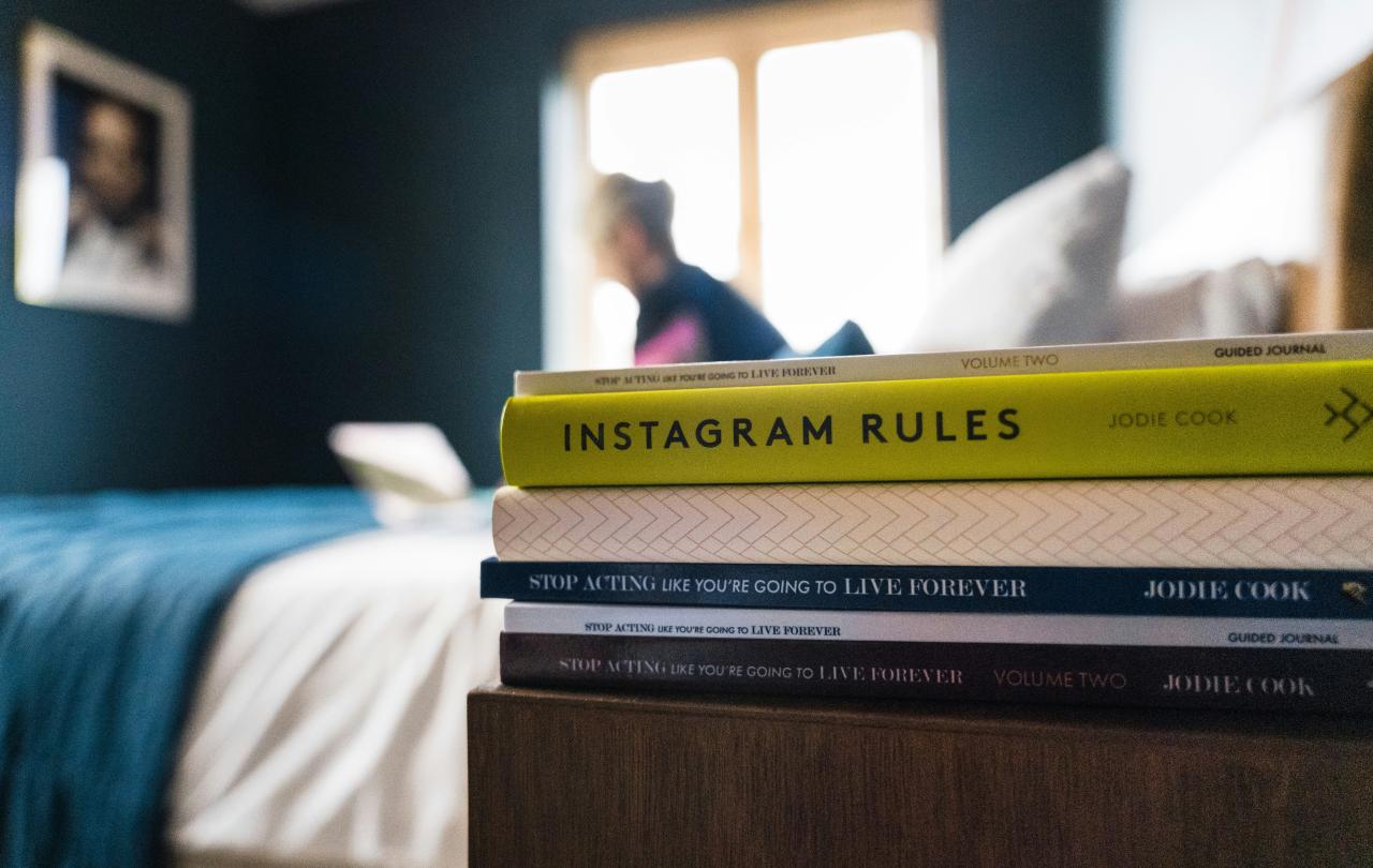 A pile of books on a bedside table.