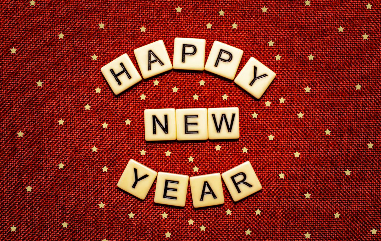 Scrabble letters read 'Happy New Year' against a red starry background.