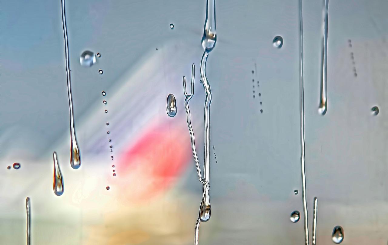 Beyond a misty and raindrop streaked window, a colourful triangle shape emerges.