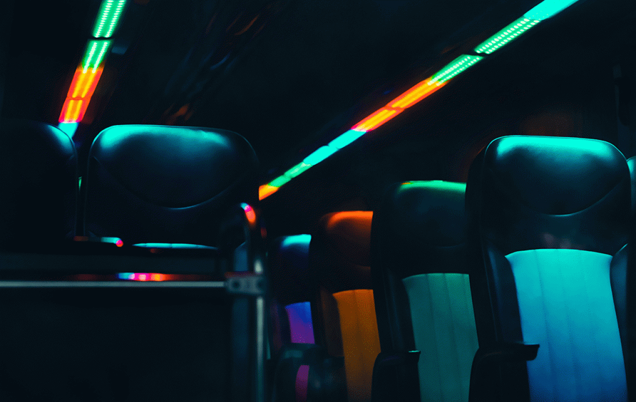 Empty bus seats are lit in dark neon colours.